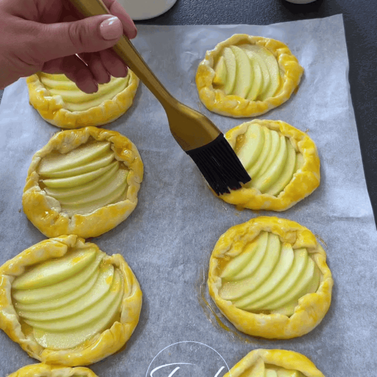 Image of Elma dilimlerini puff hamurunun daireleri üzerine fanned şeklinde yerleştirin, kenarlarda...