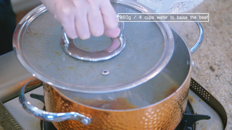 Image of When you see the amber caramelized sugar is bubbling, pour 4 cups of water into the pot. Please use a lid to protect yourself because the hot caramel will splash everywhere.