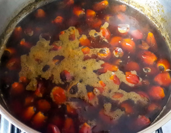 Image of To extract palm nut juice, wash and boil the nuts for 20–30 minutes until soft. Drain, then pound gently to separate the skin from the nuts. Add warm water, squeeze out the juice, and strain to remove chaff. Set the...