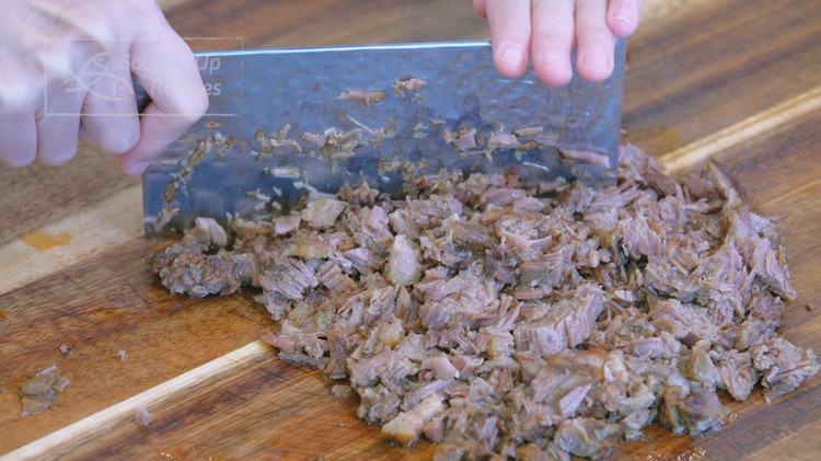 Image of Once the beef is done braising, take it out of the stockpot and chop it finely on the cutting board, adding the braising liquid in batches until the meat can no longer absorb, about 5-6 Tbsps. This is the key...
