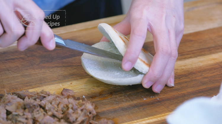 Image of Use a knife to cut a white bun (bai ji mo白吉馍) but stop in the middle. Then use the tip of the knife to wiggle the inside to create a pocket.