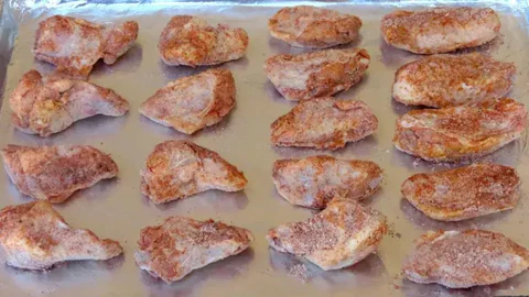 Image of Pat wings dry with a paper towel and season with the spice mixture. Coat with flour and place them skin side down onto the pan.