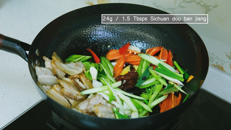 Image of Add the garlic, ginger slices, red and green chili peppers, the white parts of the garlic sprouts,   fermented black beans, sweet flour sauce, and Sichuan dou ban jiang. Stir over medium heat for a few minutes.