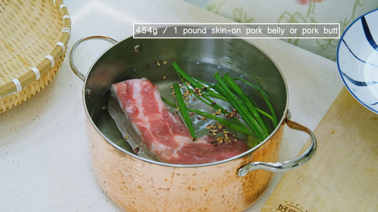 Image of Add water, the pork belly, ginger slices, scallions, Sichuan peppercorns, and Chinese cooking wine to a pot, and then bring to a boil. Switch the heat to low and simmer for 25 minutes. 