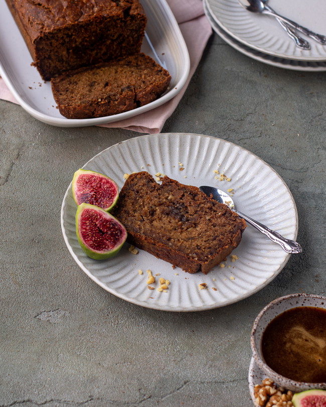 Plate with a sliced piece of cake served with fresh figs.