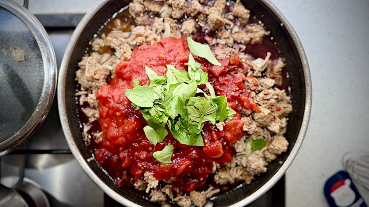Image of now add your red wine, tinned tommys and basil. Tour pan turn heat down to low, place a lid on your pan and simmer for approximately one hour or until the basil has almost completely broken down and has reduced...