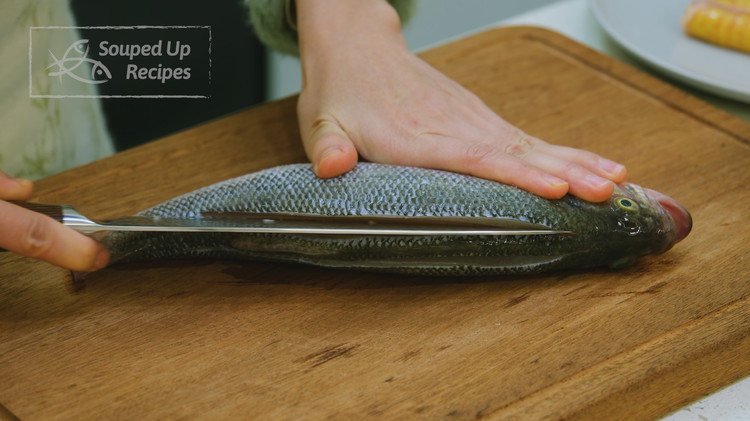 Image of Use a sharp knife to score the fish flesh along the backbone on each side. The belly part is thinner. The back part is much thicker. By scoring it, the fish can be cooked evenly.