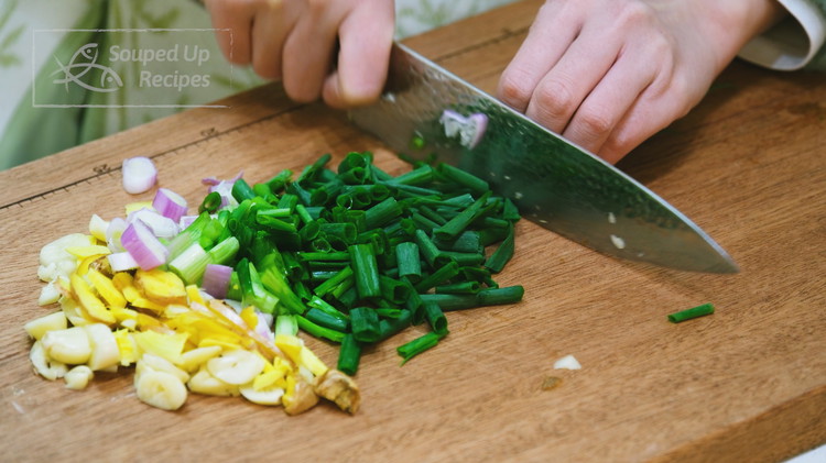 Image of Smack 5 cloves garlic, 2 inches ginger, and 3 scallions using a heavy-duty cleaver then roughly dice them.