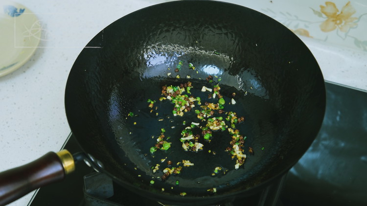 Image of Add the vegetable oil, Sichuan peppercorns, 1 tsp diced ginger, 1 tsp diced garlic, and 2 tsp diced scallion, into a saucepan and stir over medium-low heat for 3 minutes.