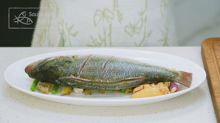 Image of Remove the aromatics from the fish and use paper towels to pat it dry. Next, lay the fish on the plate on top of the ginger and scallion stalks. These aromatics lift up the fish while steaming, allowing better air...