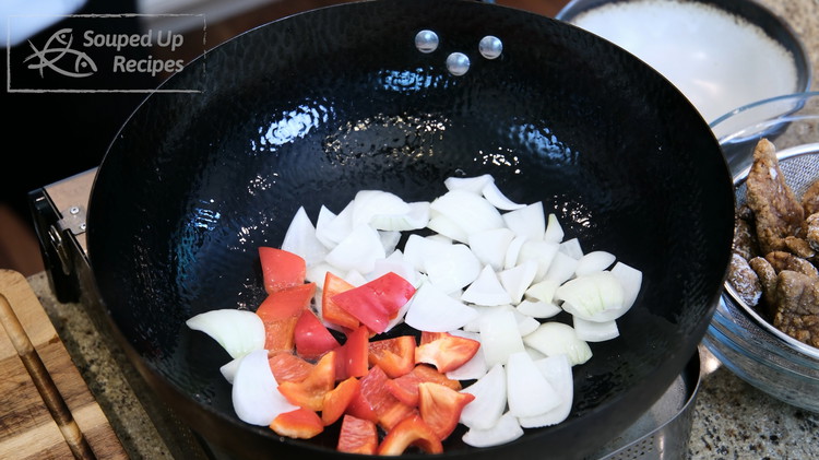 Image of Turn the heat to maximum and add the bell pepper and onion to the wok. Stir over high heat for a minute or 2. then remove the onion and bell pepper to the side.