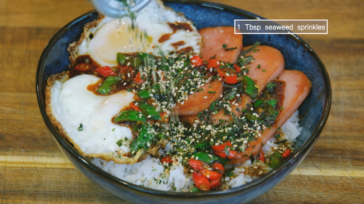 Image of Place the egg onto the rice and drizzle the sauce all over. Optionally, sprinkle some crushed, crispy seaweeds. I normally will add some roasted sesame seeds but the sea weed that I am using already contains sesame seeds.