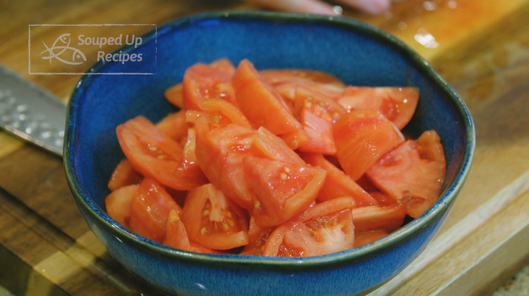 Image of Once cooled, peel the tomato skin and cut the tomatoes into bite-sized pieces. Set them aside.