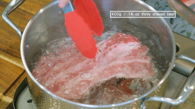 Image of Add the thinly shaved beef to the boiling water and blanch for 10 seconds. Remove the beef from the water and set it aside.