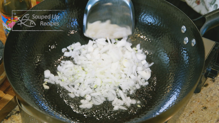 Image of Add oil and the diced onion to a wok and stir over medium heat for a few minutes or until the onion is soft.