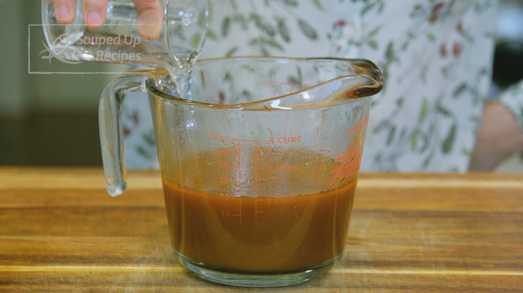 Image of Once the lamb is done simmering, take out the garlic bulbs. Pour all the broth into a measuring cup, but leave the meat and carrot behind because we want to know how much liquid we have left. You want about...