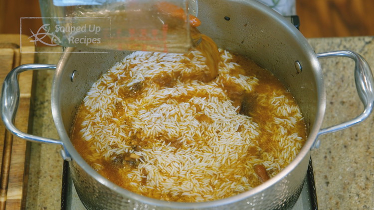 Image of Pour the broth back into the pot. Drain the rice thoroughly and add it to the pot. Spread it out evenly. Put on the lid, keep the heat at the lowest, and cook the rice for 20 minutes.