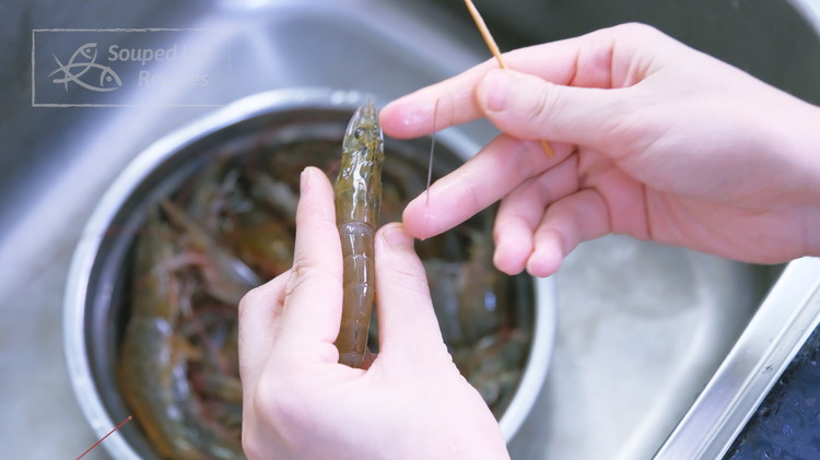 Image of While waiting, devein the shrimp by sticking a toothpick into the neck underneath the vein and then pulling it out. Once done, rinse the shrimp and drain thoroughly.