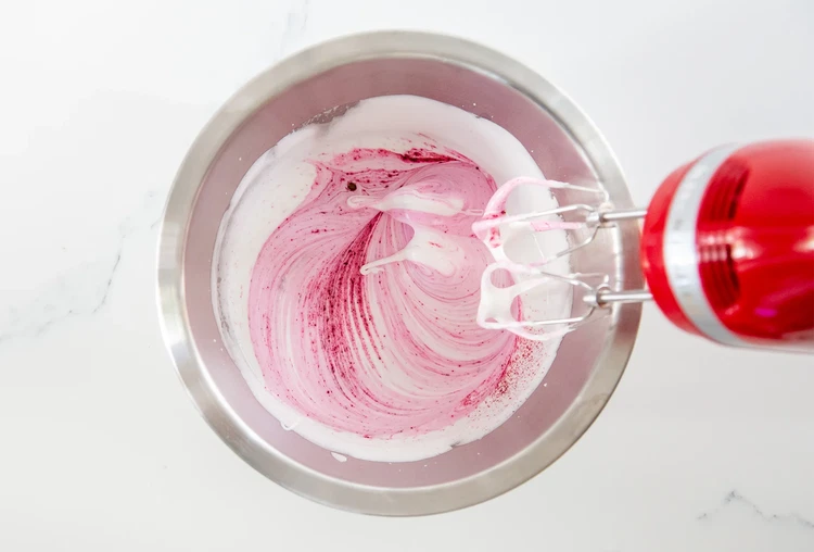 Image of Beat egg whites until foamy. Add cream of tartar and salt. Slowly beat in granulated sugar. Mix in red food coloring and whip until stiff peaks form (about 10–12 minutes).
