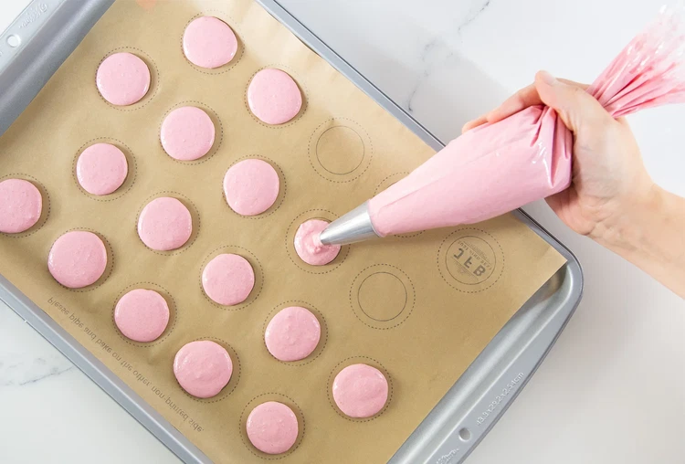 Image of Fill piping bag and pipe 40 rounds onto prepared sheets, holding the bag straight above the paper. Tap the baking sheets gently to release air bubbles. Let rest 30–90 minutes until tops are dry to the touch.