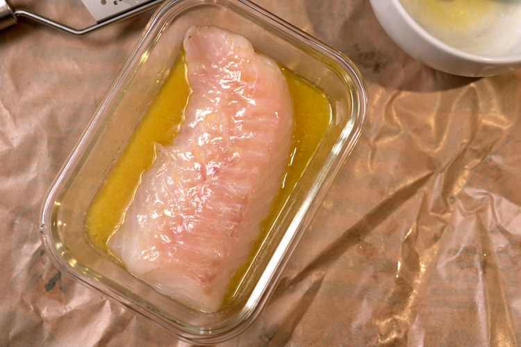Image of Marinade fish in a small container to allow the most contact between fish and marinade.  Marinade for 30 minutes to one hour flipping the fish a few times to allow more even marinading.