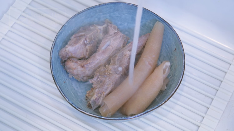 Image of Discard the blanching water and rinse the pork skin and bones under running water to wash off the foamy scum.