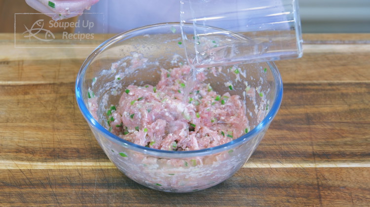 Image of Pour ¼ cup water into the pork mixture in batches and stir the meat with a circular motion in one direction to develop the texture. Add a little bit more and continue to stir until all the water is well...