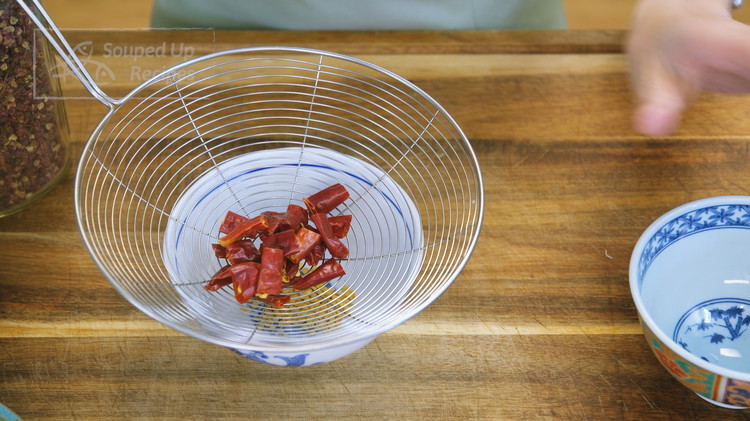 Image of Cut 8 dried red chilies into 1/2 inch long pieces. Then, use a strainer to shake off the seeds. 