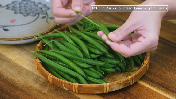 Image of Snap the tip of the green beans, then pull to remove the fiber. This step is time-consuming, but if you don't do it, your green beans will end up chewy and stringy. 