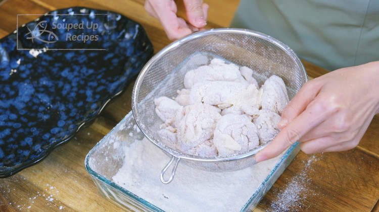 Image of Put all the coated chicken into a strainer and shake to remove the excess flour. Set the chicken aside.