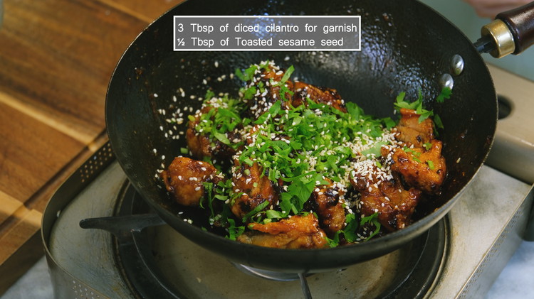 Image of Add the fried chicken and toss until every piece is coated nicely. Sprinkle 3 tbsp of diced cilantro and 1/2 tbsp of roasted sesame seeds. Give it a final toss and you are done.