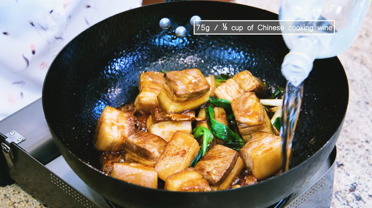Image of Add the pork belly back into the wok. Pour the Chinese cooking wine from the side of the wok and stir to evaporate the alcohol.