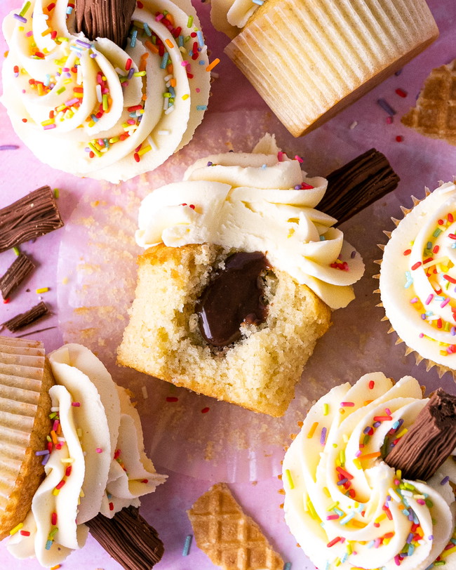 Vanilla cupcake with a chocolate ganache center, topped with vanilla buttercream, colorful sprinkles, and a Cadbury Flake, inspired by the classic 99 ice cream