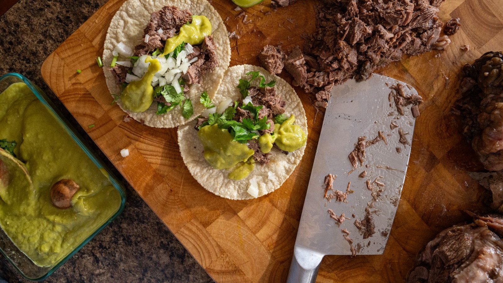 Tacos de Lengua topped with onion, cilantro, and avocado salsa