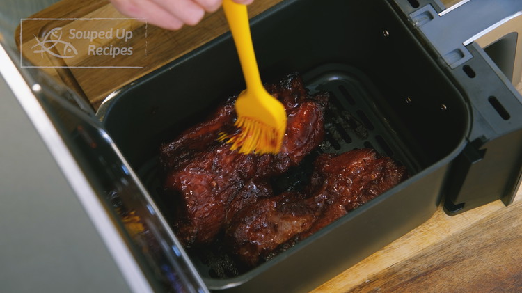 Image of After 18 minutes, brush the extra sauce left in the bowl on the meat surface. Flip and brush the other side. Stick the pork back into the air fryer and cook at 300F for another 18 minutes.