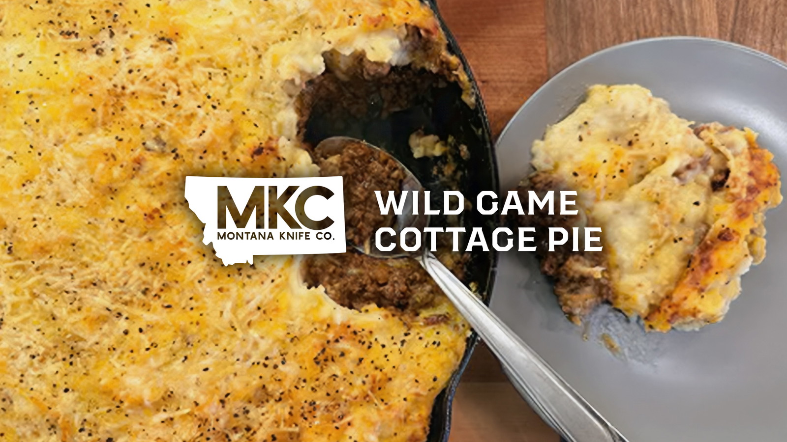 A cast iron skillet filled with wild game cottage pie topped with golden mashed potatoes and cheese.