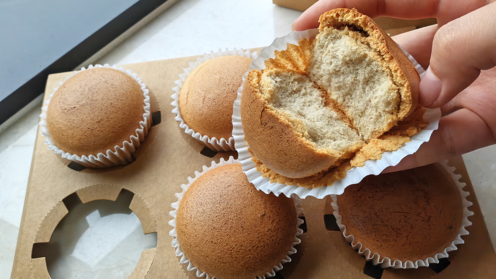 A black tea cupcake being held in the hand.