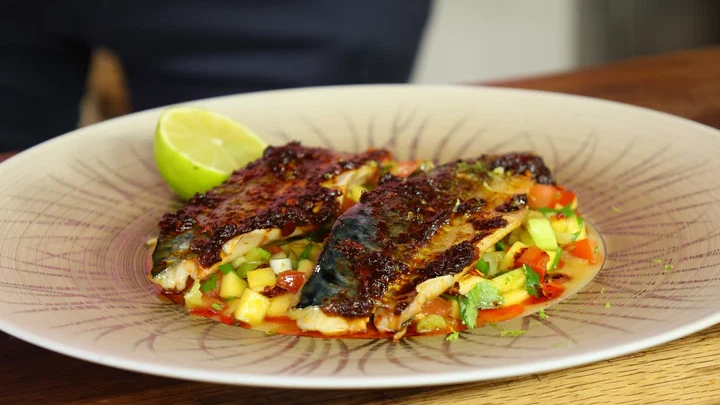 white round plate filled with tropical mango salad and grilled mackerel with RoniB's Kitchen Black Bean Chilli Paste