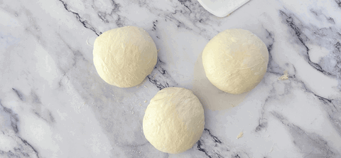 Image of Shape each piece into a circle using your bench scraper to create tension on the dough. 