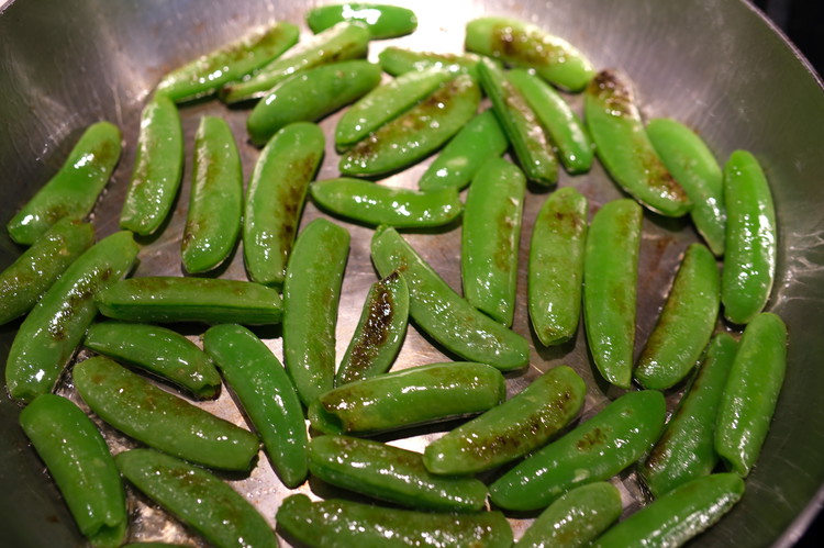 Image of When oil is hot add the snap peas and cook for about a minute or two stirring occasionally.  You are looking to quickly blister the peas but keep the green, fresh snap—they should NOT cook all the way through.