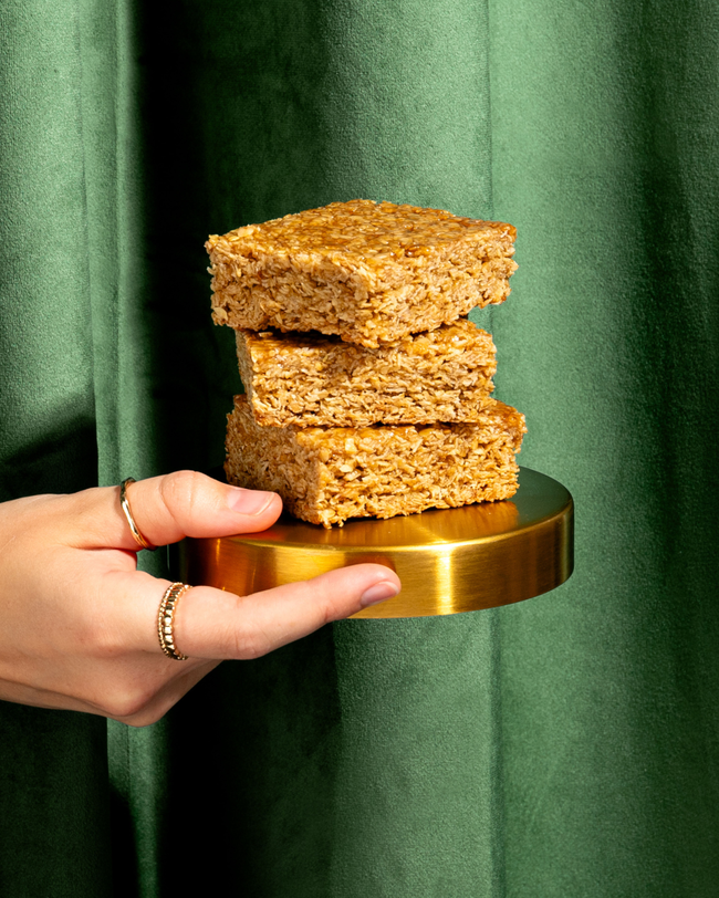 A flapjack cut in squares, piled onto a golden plate