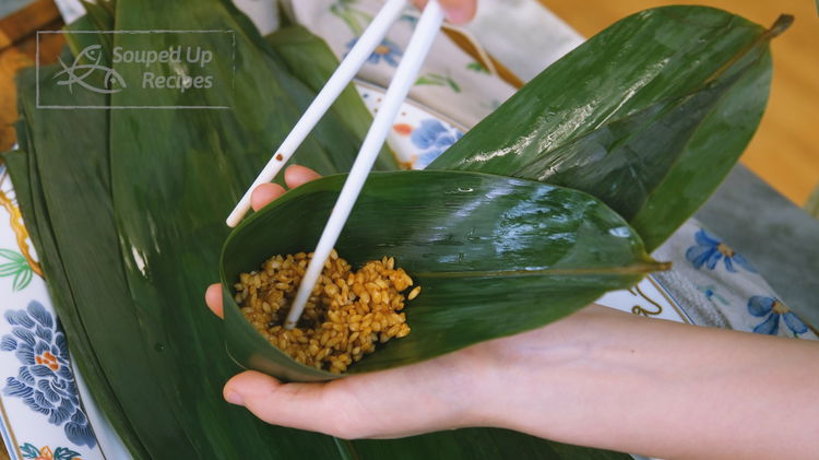 Image of Put some glutinous rice in the bamboo cone. Use a...