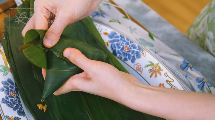 Image of Tightly pack the rice using a spoon. Fold the upper leaves down. Then, fold the side edge down. Do the same thing to the other side. Pinch the front and fold it to the side. You should get something that...