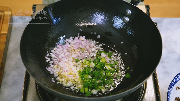 Image of Turn the heat to medium. Add 3 Tbsp of cooking oil, 3 tbsp of minced garlic, 3 tbsp of diced shallot, and 3 tbsp of minced scallion to a wok. Sauté over low heat for a few minutes until the...