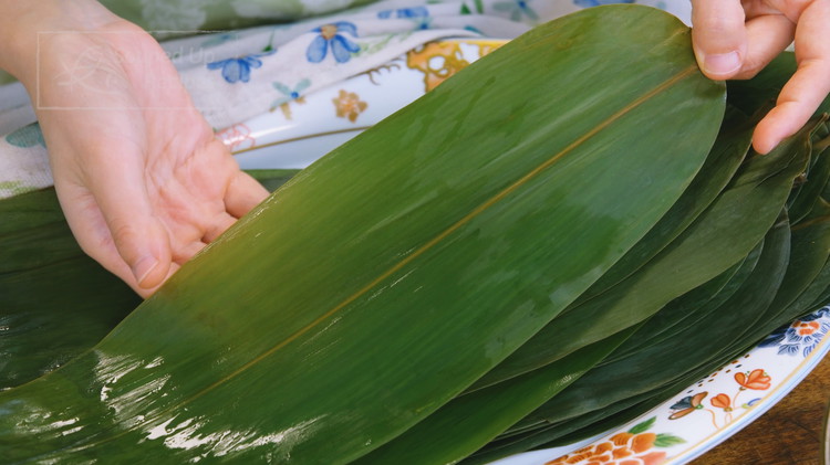 Image of Before wrapping, please distinguish between the rough and smooth sides of the bamboo leaves. The rough side has a convex stem; it should be facing out when wrapping. The smooth side is non-stick so it should be in contact with the glutinous...