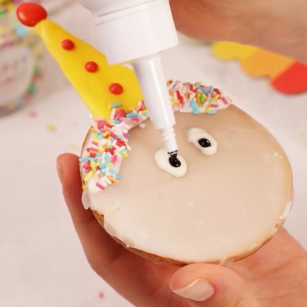 Image of Gesicht gestalten: Zeichne mit dem Creamy White Drip zwei kleine Punkte als Augen auf.  Mit etwas schwarzem Drip oder einem Lebensmittelstift malst du die Pupillen hinein – süßer Augenaufschlag inklusive!