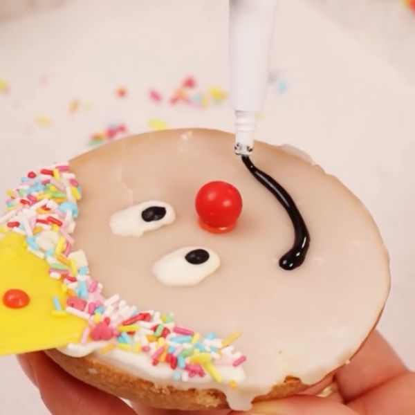 Image of Für das breite Clown-Lächeln einfach einen gebogenen Mund mit schwarzem Drip malen – am besten gleich zwei kleine Schokokugeln an die Mundenden setzen.