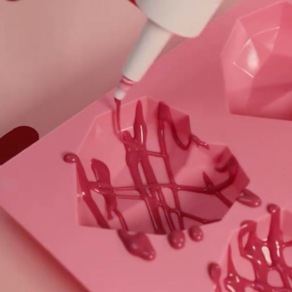 Image of Wenn du den Effekt wie auf dem Bild haben möchtest nimmst du erst den pinken Drip und machst Zick-Zack Bewegungen ein Muster in die Herz-Diamant Form und lässt das ganze für 10 Minuten hart werden.
