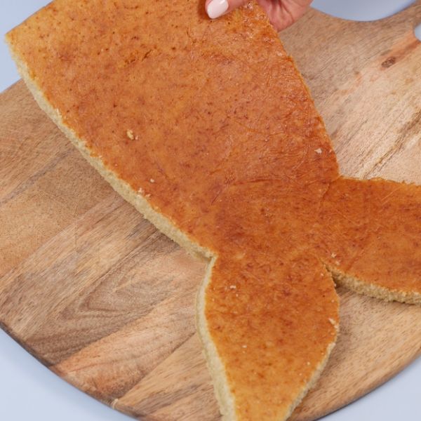 Image of Flossenform ausschneiden:Schneide aus dem Biskuit vorsichtig eine große Flosse aus. Wer sich das Freihand nicht zutraut: Einfach eine Flosse aus Papier ausdrucken und als Schablone nutzen. Die untere Hälfte bildet den Schwanz, die obere den Flossenansatz.