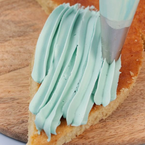 Image of Flossenschwanz aufspritzen:Befülle einen Spritzbeutel mit Sterntülle und einer Farbe deiner Wahl. Damit den unteren Teil der Flosse (also den Flossenschwanz) aufspritzen – schön fächerförmig, wie im Video.